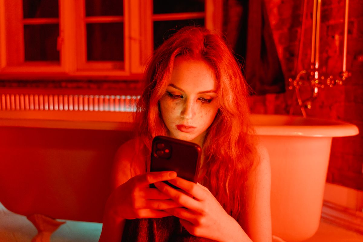 Kirmizi isik altinda telefon kullanan kadin